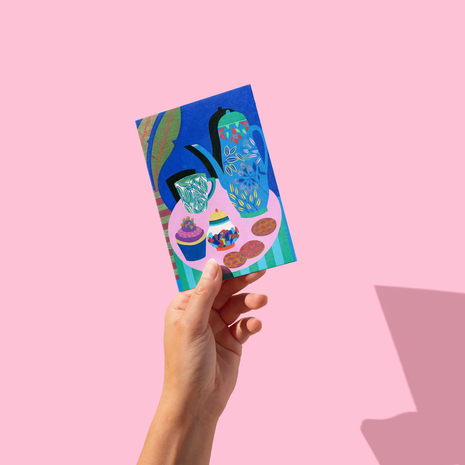 Théière bleue, gâteaux et tasse sur table rose, fond bleu profond, carte postale illustrée par Orane Sigal