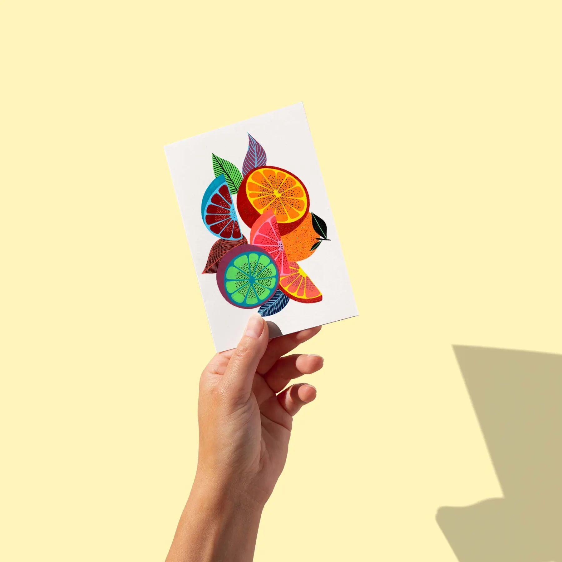 Agrumes coupés aux pulpes multicolores entourés de feuilles graphiques, carte postale illustrée par Orane Sigal