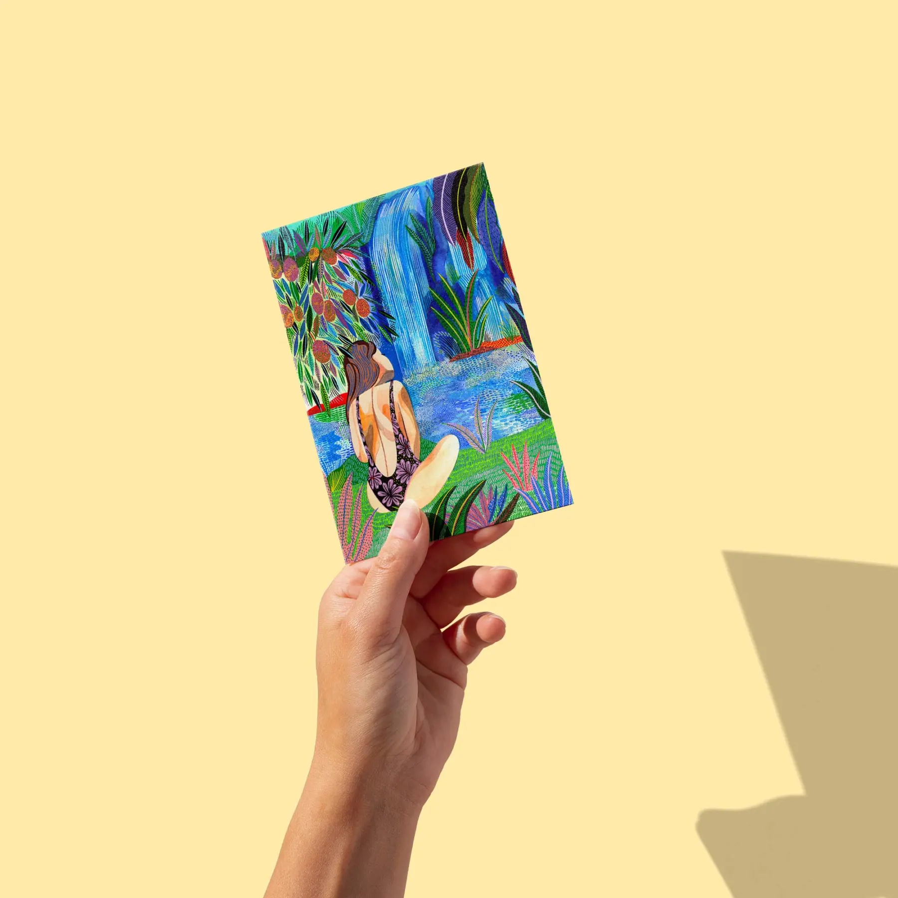 Femme de dos assise au bord d'une cascade tropicale, manguier et végétation verte luxuriante, carte postale illustrée par Orane Sigal