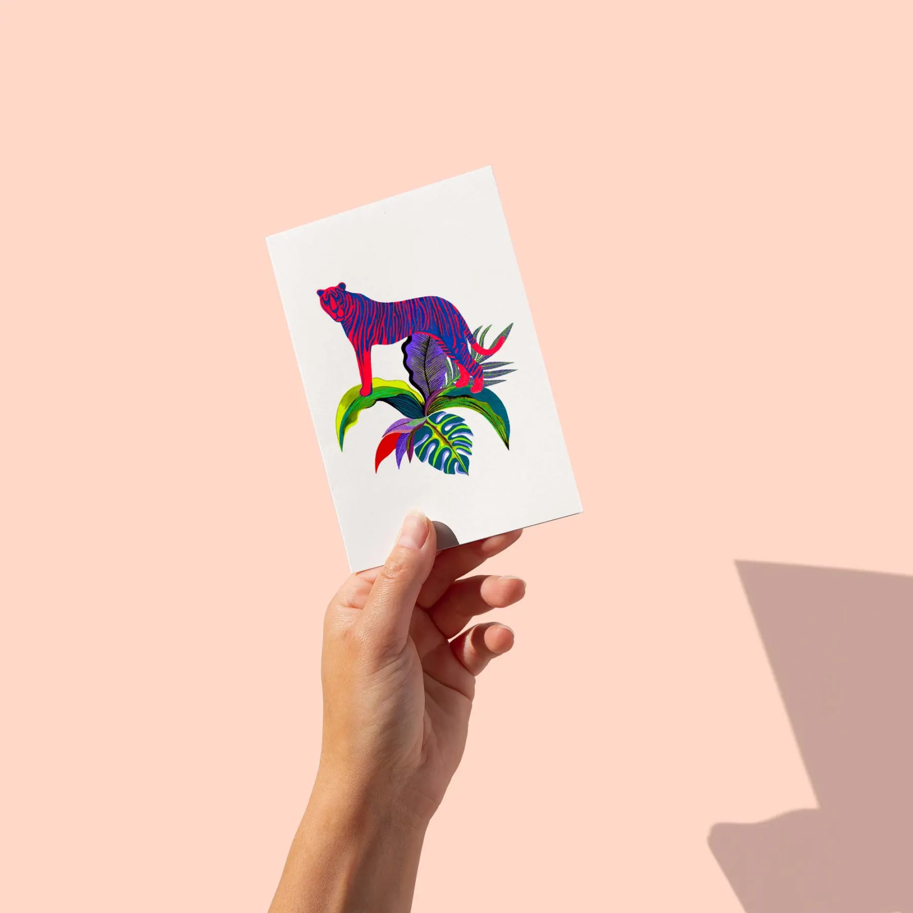 Tigre rose et bleu debout sur des feuillages tropicaux, fond blanc, carte postale illustrée par Orane Sigal
