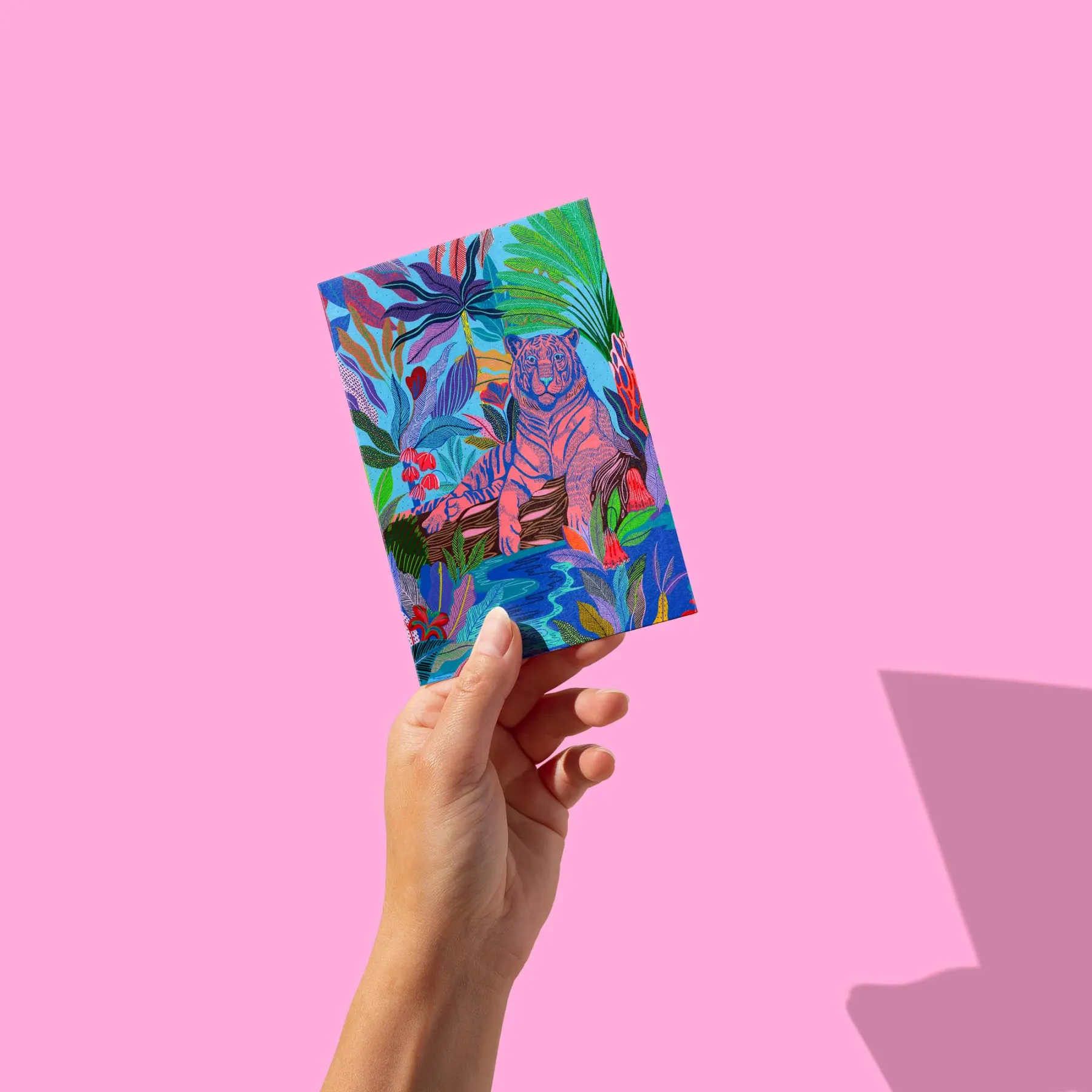 Tigre rose allongé sur un tronc près d'une rivière, jungle bleue colorée, carte postale illustrée par Orane Sigal