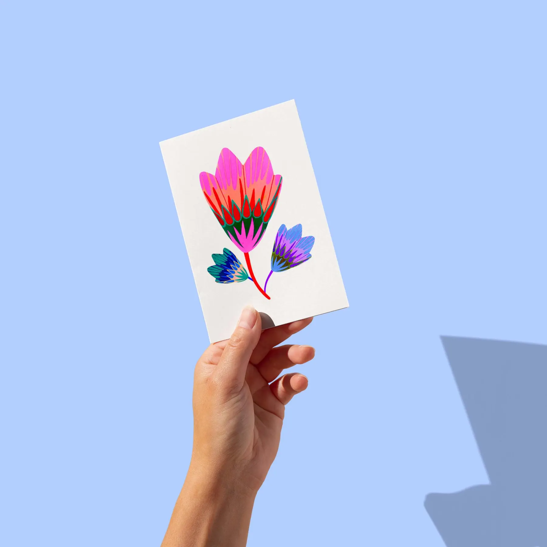 Grande fleur rose stylisée et deux fleurs bleues sur fond blanc, carte postale illustrée par Orane Sigal