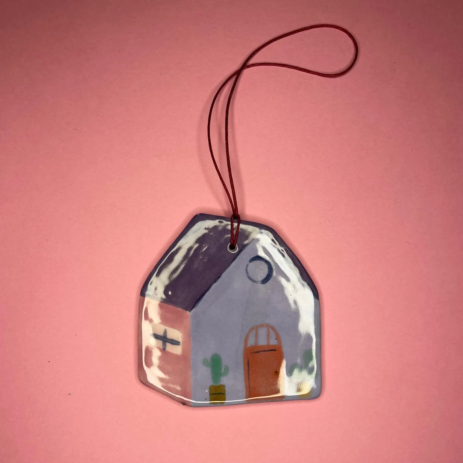 Maisonnette en céramique au toit violet sur fond rose, illustration par Orane Sigal
