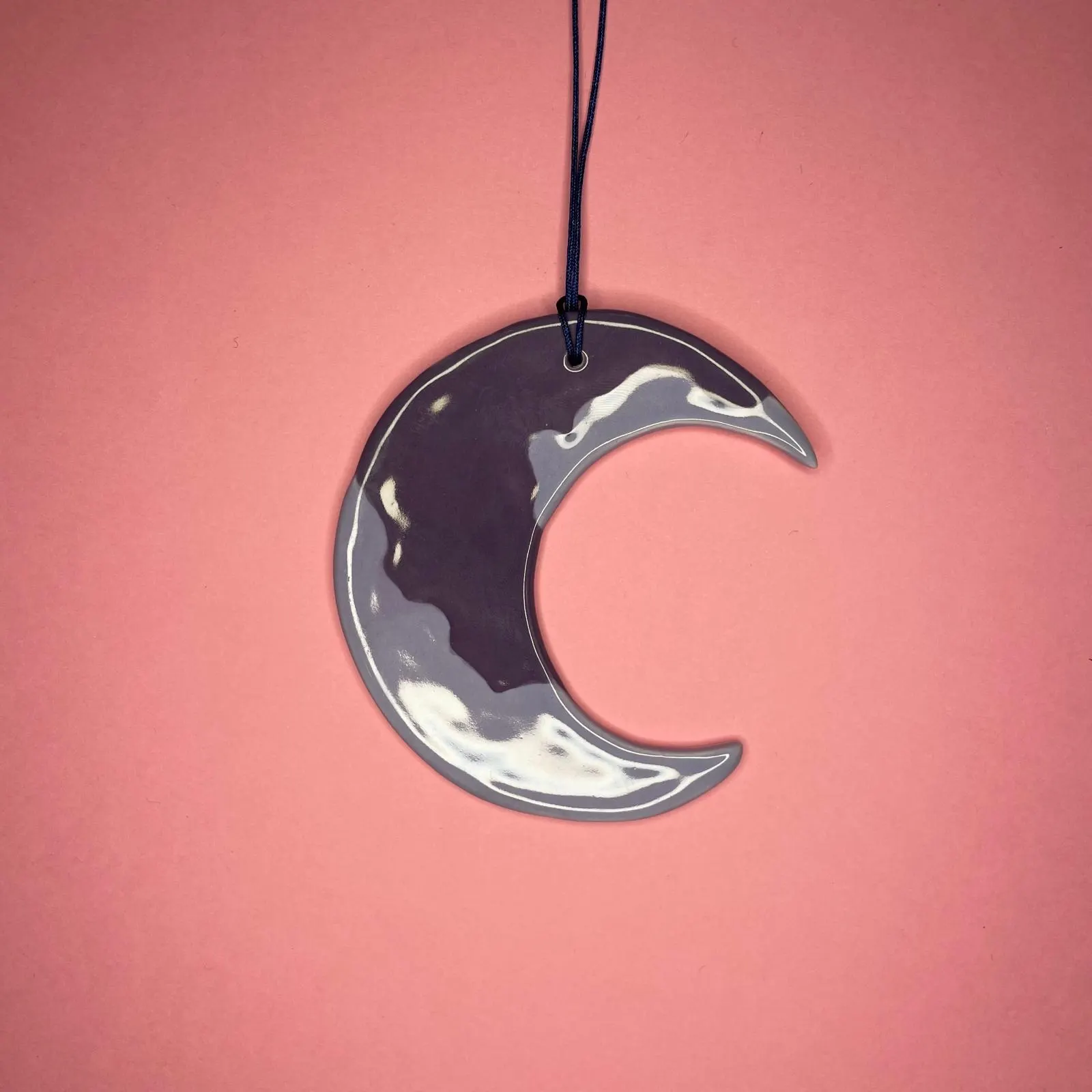 Croissant de lune en céramique gris nacré sur fond rose, illustration par Orane Sigal