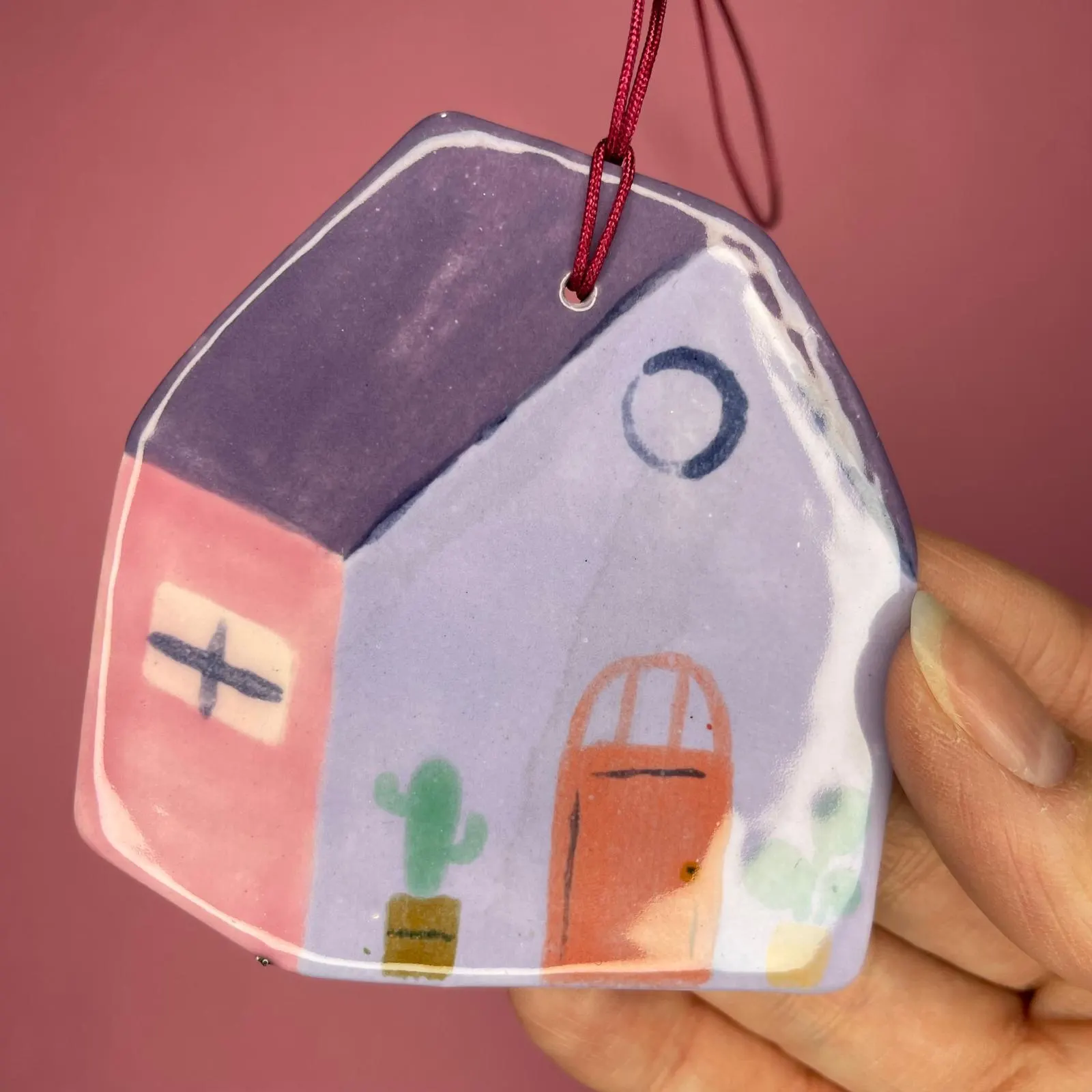 Maisonnette en céramique au toit violet sur fond rose, illustration par Orane Sigal